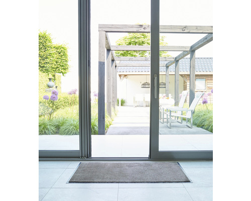 Paillasson devant une porte coulissante donnant sur une terrasse avec mobilier de jardin