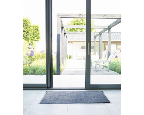 Graue Fußmatte vor einer Terrassentür mit Blick auf eine Terrasse