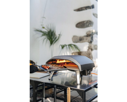 Ooni Gas Pizzaofen mit Speisen auf einem Tisch im Freien.