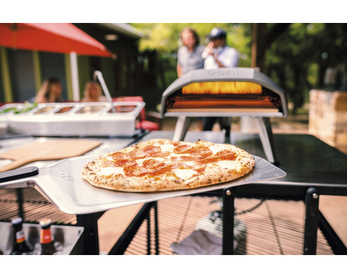 Scène avec pizza sur une pelle à pizza et un four à pizza à l''extérieur