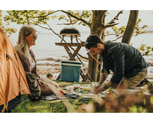 Scène d''extérieur avec un homme préparant des pizzas, une femme et une tente.