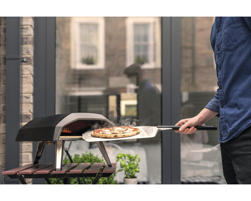 Une pizza est retirée d''un four à pizza à l''aide d''une pelle à pizza.