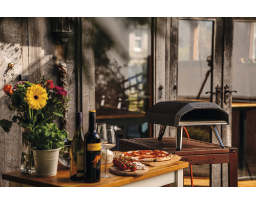 Scène d''extérieur avec four à pizza, pizza, vin et fleurs