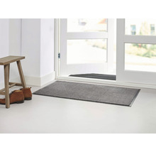 Zone d''entrée avec paillasson, tabouret et chaussures devant une porte