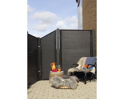 Balcon avec éléments de protection visuelle en plastique, table en rotin et fauteuil avec fourrure