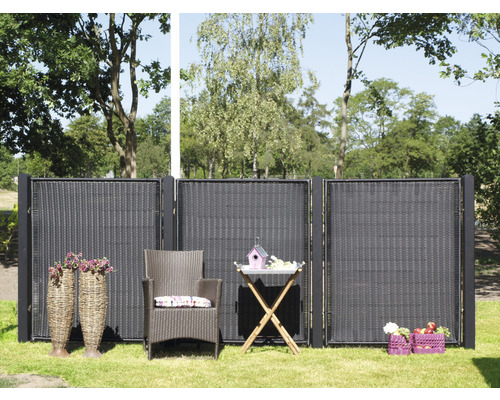 Scène de jardin avec pare-vue, fauteuil en rotin et table de jardin