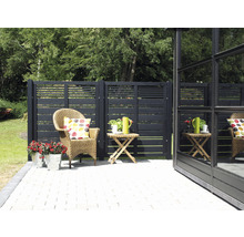 Gartenszene mit Holzzaun, Korbsessel, Beistelltisch und Blumen