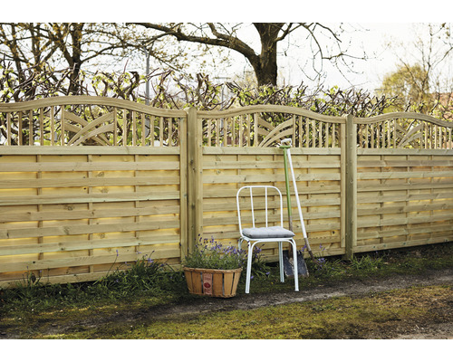 Clôture en bois avec finition décorative, chaise de jardin et panier à plantes dans le jardin