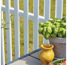 Detailaufnahme eines weißen Gartenzauns mit dekorativen Elementen auf einem Tisch