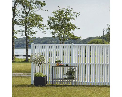 Scène avec clôture de jardin blanche, plantes en pot et table de jardin