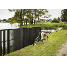 Schwarzer Holzzaun mit Fahrrad auf Rasen am See