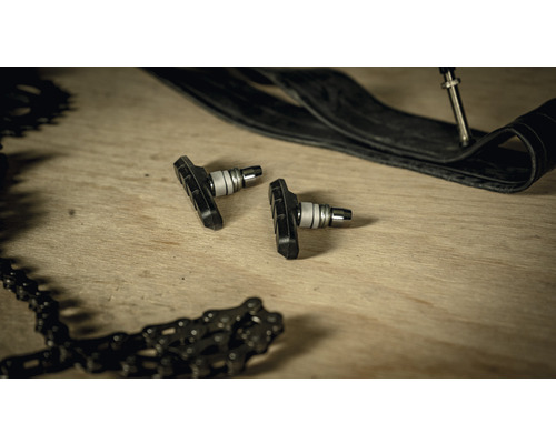 Fahrrad-Bremsbeläge, Fahrradkette und Fahrradreifen auf einem Holztisch