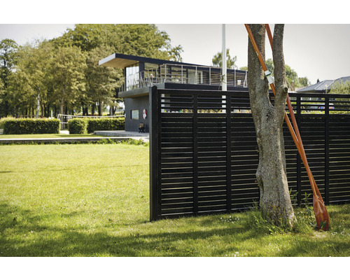 Scène avec clôture en bois, arbre et bâtiment en arrière-plan