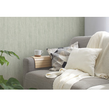 Wohnzimmer mit gemusterter Tapete, Sofa mit Kissen und Tagesdecke