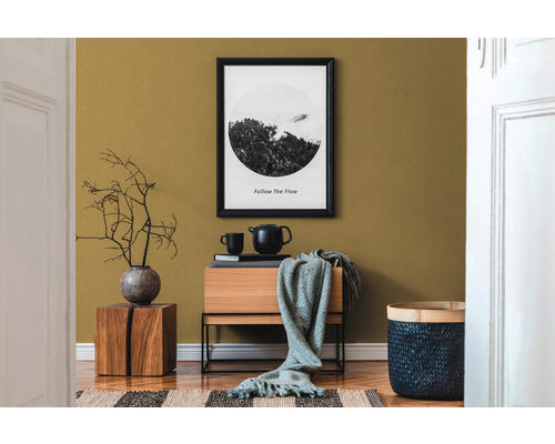 Dekoratives Wohnzimmer mit Holzmöbeln, Textilien und einem gerahmten Bild an der Wand