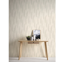 Espace décoratif avec un papier peint orné de motifs de plumes, une table en bois et divers éléments décoratifs.