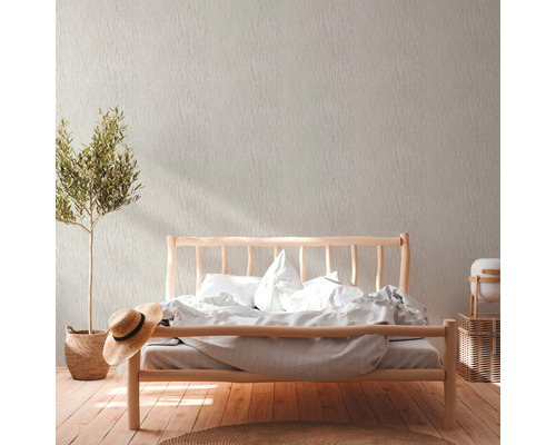 Helles Schlafzimmer mit Holzbett, Zimmerpflanze und gemusterter Tapete.