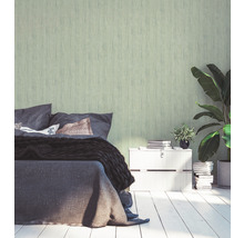 Schlafzimmer mit Bett, Nachttisch, Zimmerpflanzen und grüner Tapete