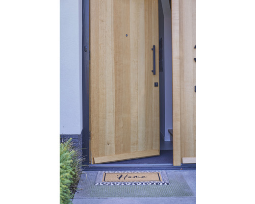 Geöffnete Haustür mit Fußmatte mit der Aufschrift Zuhause