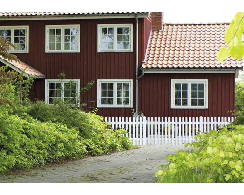 Landhaus mit Holzwänden und weißem Lattenzaun