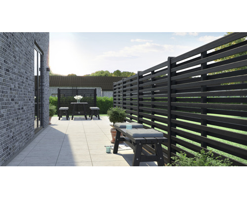 Terrasse avec clôture en bois, banc et groupe de tables dans le jardin.