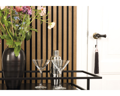 Dekoratives Interieur mit Barwagen, zwei Martini-Gläsern, Cocktailshaker, Blumenstrauß, Wandpaneelen und einer Tür
