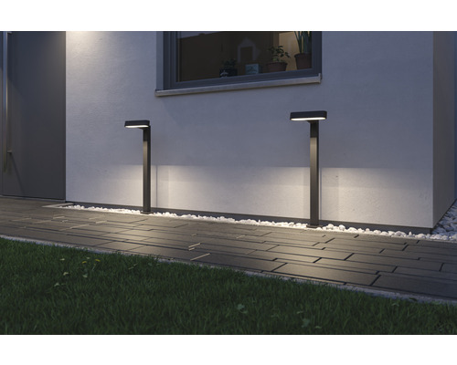 Zwei Aussenleuchten beleuchten einen Gehweg vor einem Haus.
