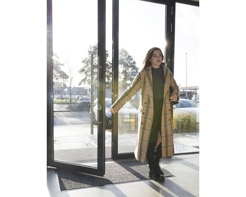 Eingangsbereich mit Fussmatte und einer Frau, die eine Tür öffnet