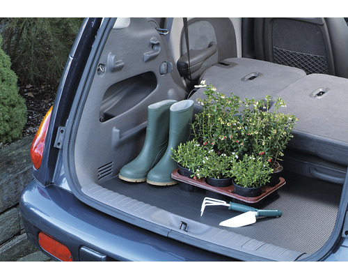 Kofferraum eines Autos mit Gummistiefeln, Pflanzen und Gartengeräten auf einer Kofferraummatte