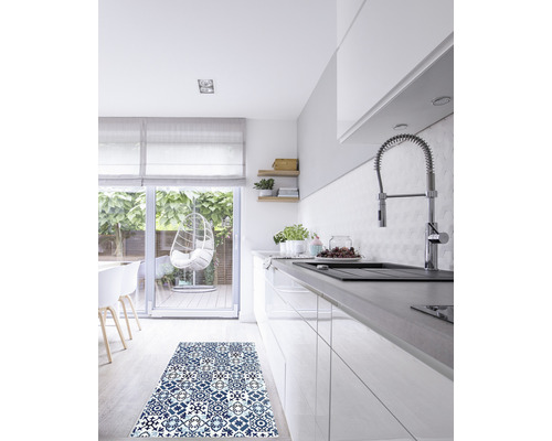 Scène de cuisine avec un tapis bleu à motifs devant une armoire de cuisine blanche