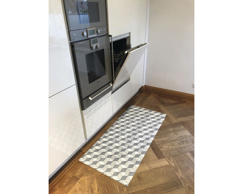 Cuisine avec appareils intégrés et un tapis rectangulaire à motif de cubes sur un plancher en bois