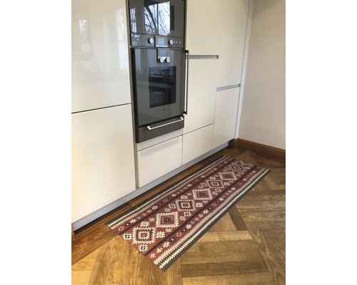Cuisine avec four encastrable et tapis à motifs sur plancher en bois