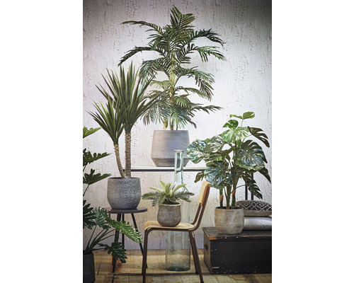 Arrangement de différentes plantes artificielles en pot sur une table et une chaise devant un mur