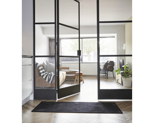 Vue d''une pièce avec un paillasson noir et une porte en verre avec cadre en acier