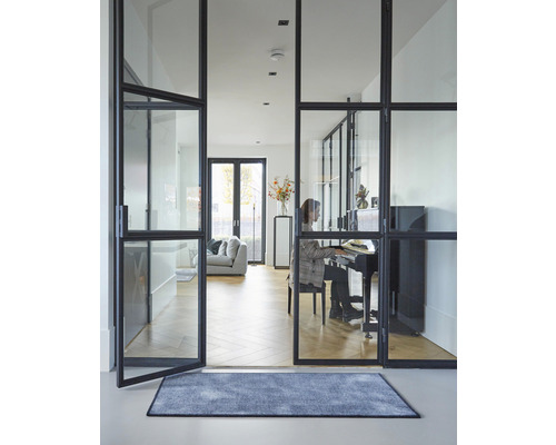 Photo d''intérieur d''une pièce à vivre avec des portes en verre, un tapis et une personne jouant du piano.