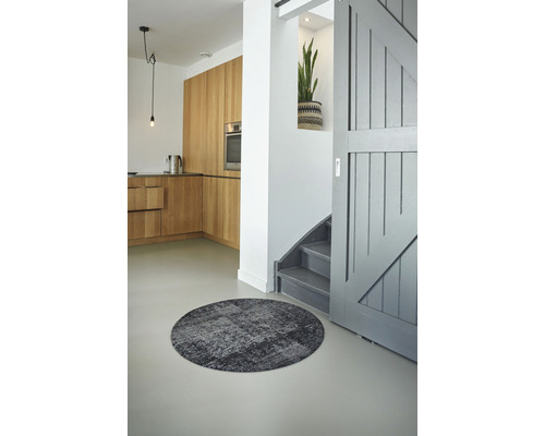 Intérieur avec tapis rond, cuisine et escalier.