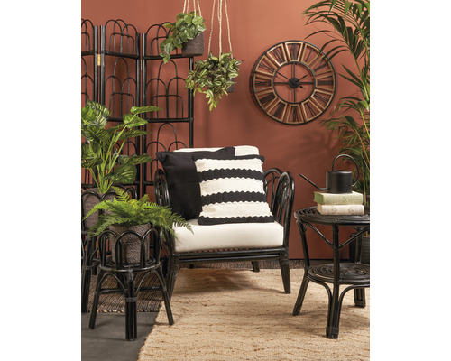 Wohnzimmer mit Rattansessel, Beistelltisch, Raumteiler, Wanduhr und Zimmerpflanzen für eine gemütliche Atmosphäre