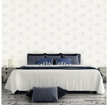 Chambre avec papier peint à motifs floraux, lit et tables de chevet.