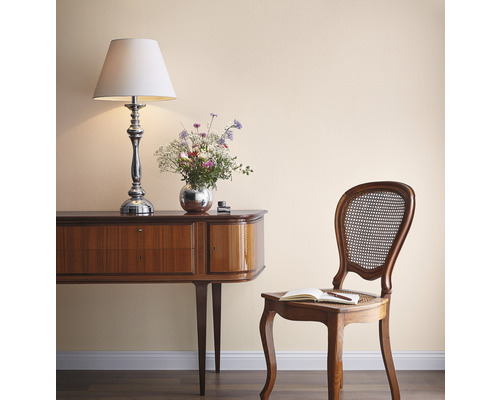 Vue intérieure avec commode, lampe, fleurs, chaise et carnet devant un mur structuré