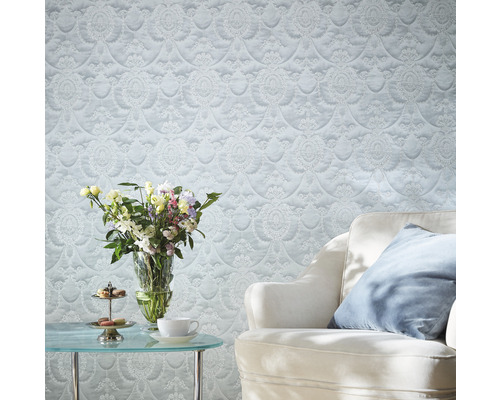 Salon avec papier peint à motifs, table avec fleurs et fauteuil