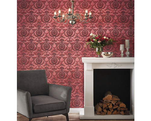 Salon avec papier peint à motifs rouge, cheminée et fauteuil