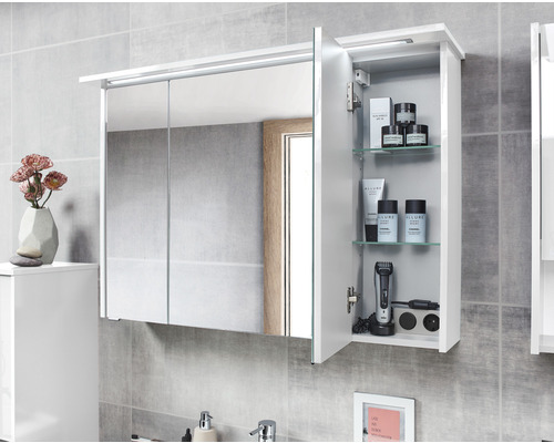 Armoire de toilette avec éclairage LED et porte ouverte, vue sur étagères en verre et accessoires de salle de bain