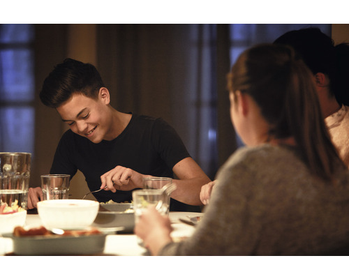Personnes assises à une table à manger avec de la vaisselle et des aliments