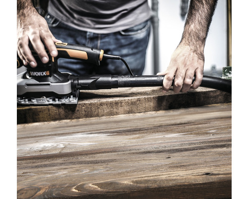 Mann schleift Holzbrett mit einem Multischleifer mit Staubabsaugung von Worx