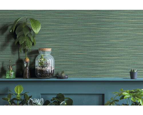 Dekorative Zimmerpflanzen und eine grüne Struktur-Tapete auf einer Ablage