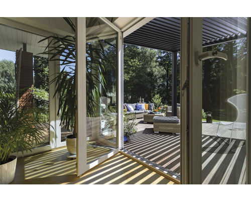 Blick durch eine Glastür auf eine Terrasse mit Gartenmöbeln und einer Pergola