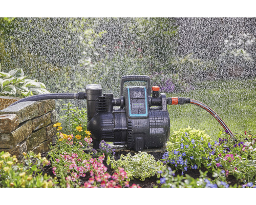 Système automatique d''alimentation en eau domestique Gardena en fonctionnement avec irrigation dans le jardin.