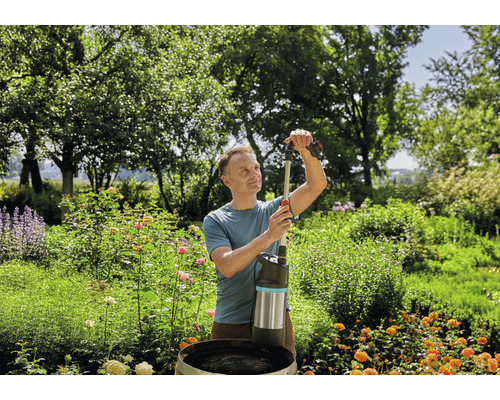 Un homme utilise une pompe de citerne d''eau de pluie dans le jardin.