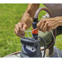 Une personne fixe une corde à une pompe de jardin avec raccord de tuyau