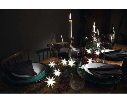 Festlich gedeckter Tisch mit Tellern, Gläsern, Kerzen und Sternenlichterkette für eine stimmungsvolle Atmosphäre